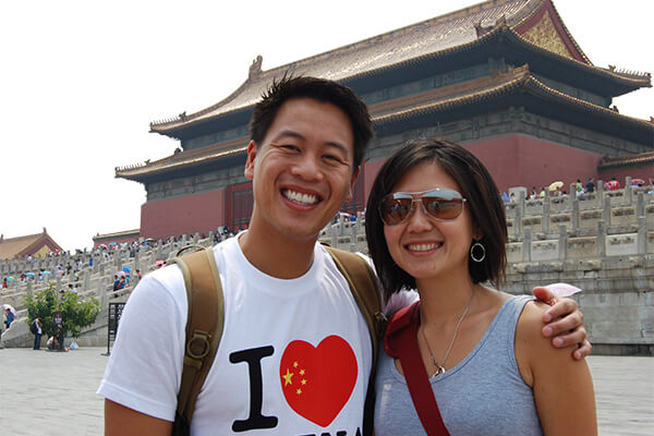 Two students pose in front of a large Chinese building