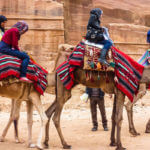 Two tourists riding camels in Jordan