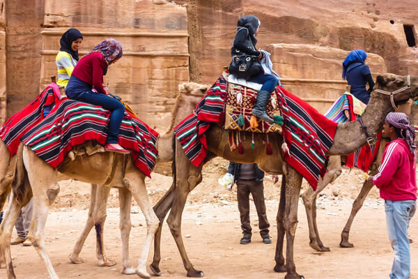 Two tourists riding camels in Jordan