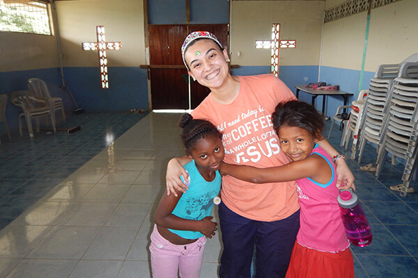 A student hugs two children from her Ecuador service learning study abroad program