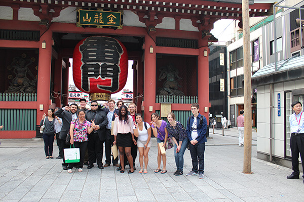 A group of students poses in front of a Chinese building featuring an ornate traditional lantern