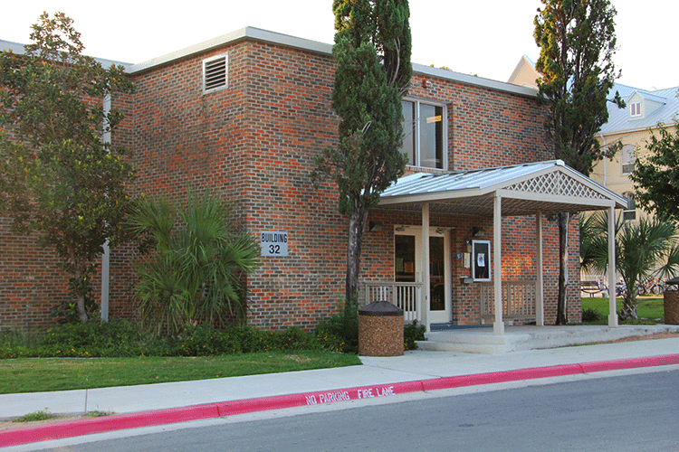 Front entrance of Lourdes Hall, a two-story brick building with a covered entryway