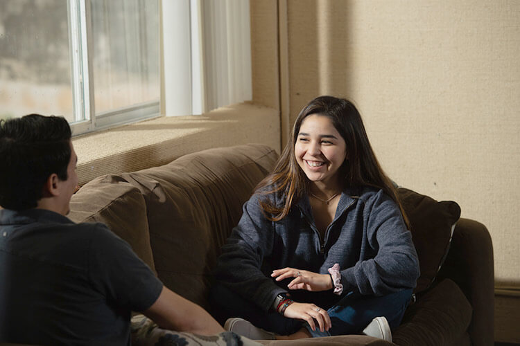 Female student sitting in a common room smiles