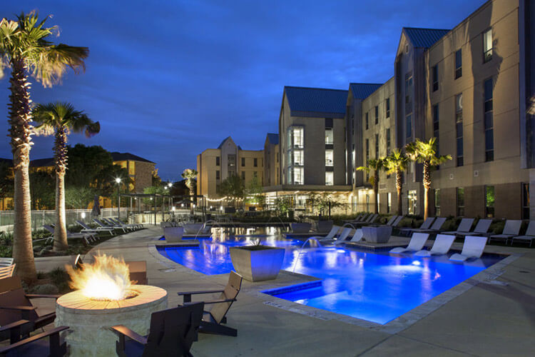 Fire pit and patio surrounding the pool at Perigueux at nighttime